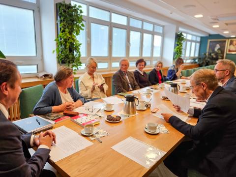 Grupa ludzi siedzi przy stole w sali konferencyjnej podczas spotkania grona redakcyjnego Kroniki Miasta Poznania