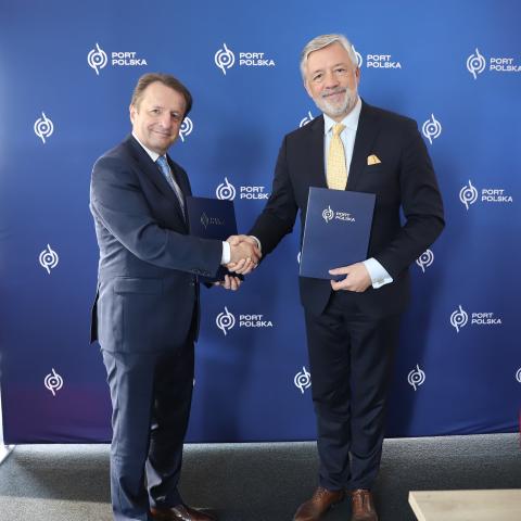 Rektor UPP prof. Krzysztof Szoszkiewicz i prezes spółki CPK Filip Czernicki ściskają sobie dłoń, trzymając w rękach podpisaną umowę