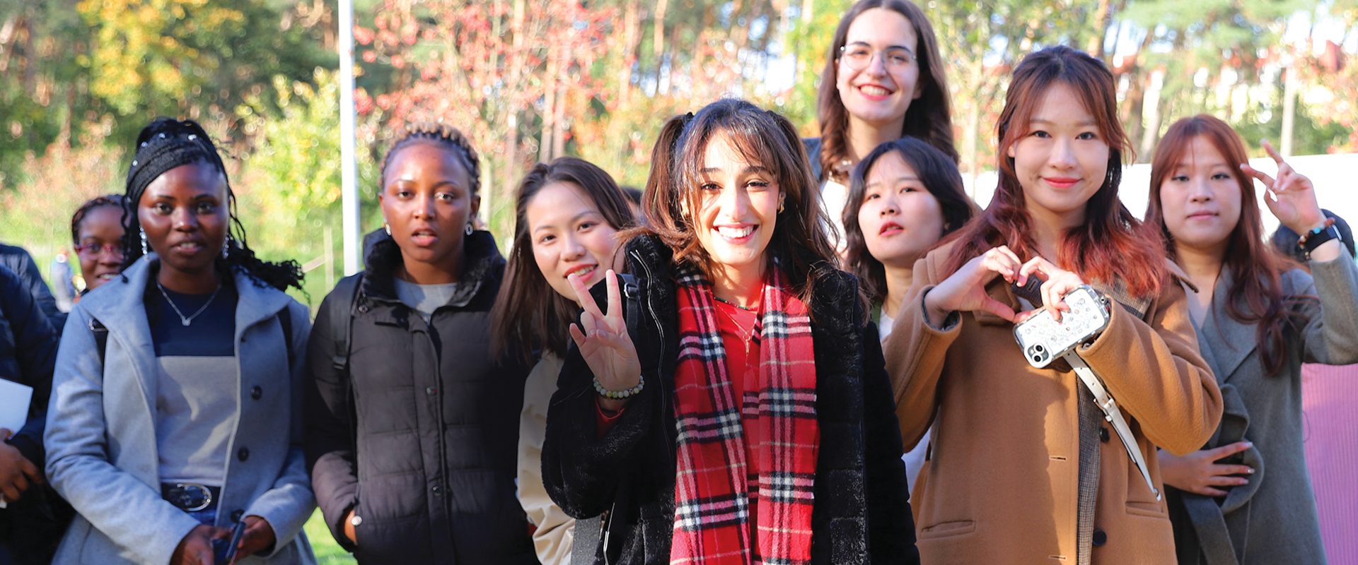 Grupa ludzi z różnych krajów pozująca do zdjęcia przed budynkiem