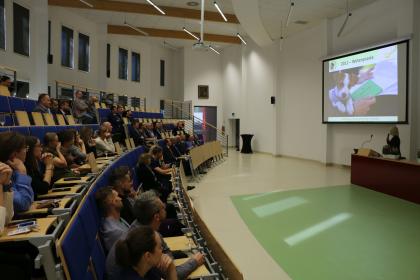 Grupa osób w sali wykładowej patrzy na ekran