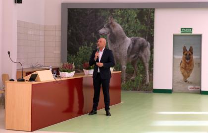 Mężczyzna w garniturze z widokiem na ścianę z obrazem psa.