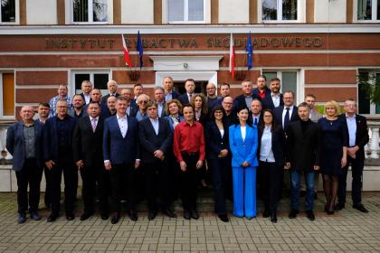 Grupa ludzi stoi przed budynkiem