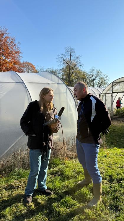 Dwie osoby rozmawiające przed szklarnią