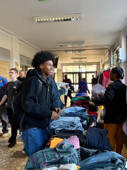 Grupa osób na korytarzu przegląda ubrania