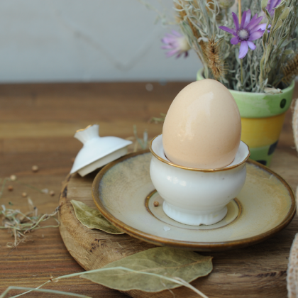 Jajko w jajku stoi na drewnianym stole z kwiatową koncepcją stylu eko