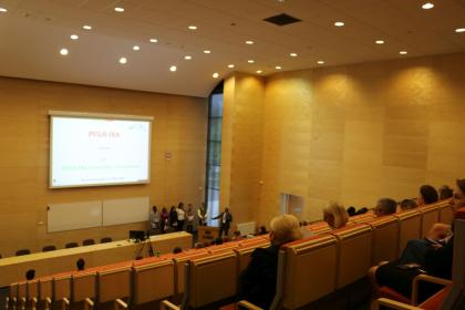  Przestronna sala wykładowa z ekranem do projekcji i uczestnikami.