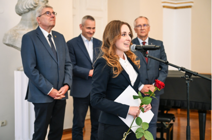 Kobieta podczas przemówienia, w tle trzech mężczyzn