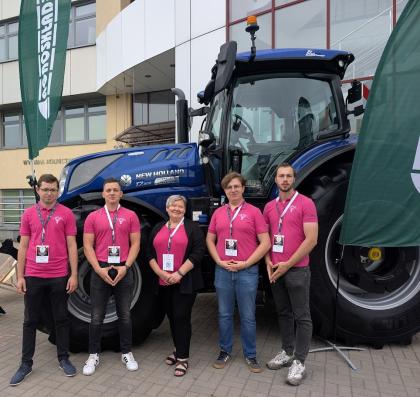 Grupa osób, w tle traktor